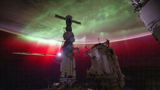 The aurora glows behind the International Space Station, which was stopped by the Russian Soyuz spacecraft. Also visible as a bright light is the moon.